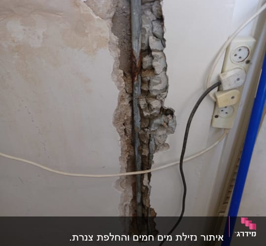 צינור חלוד בקיר חשוף עם חוטי חשמל